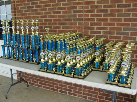 2007 Ford Mustang - Numerous trophies are arranged on tables in front of a brick building.
