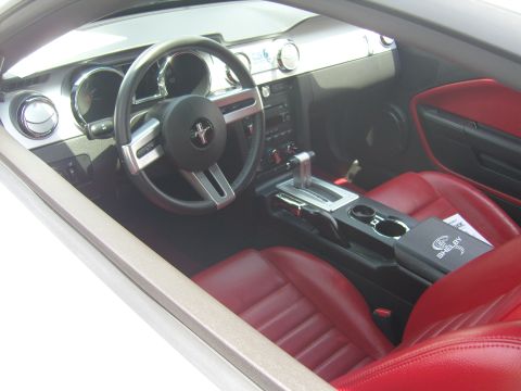 2007 Ford Mustang - The interior of a car features red leather seats and a center console with a Shelby logo.