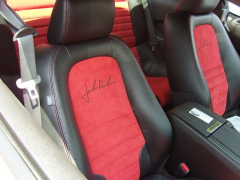 2007 Ford Mustang - The interior of a car shows black leather seats with red suede inserts and red stitching.
