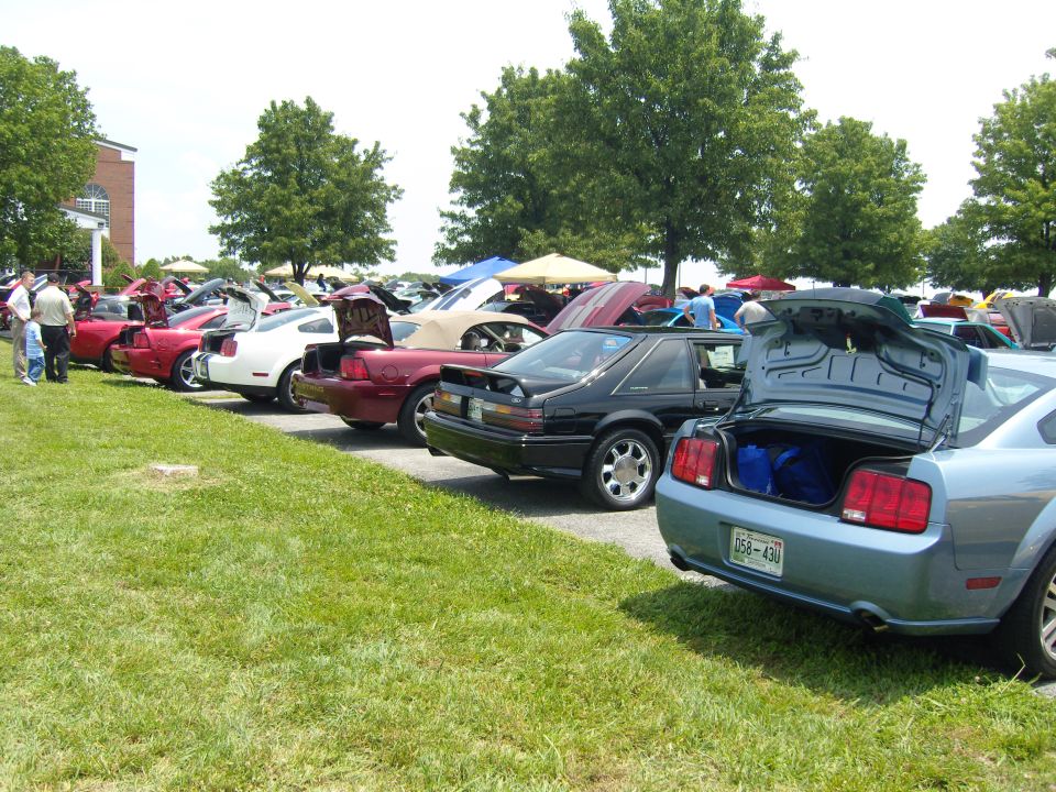 Light blue 2005 Ford Mustang rear view with open trunk and blue bags inside
