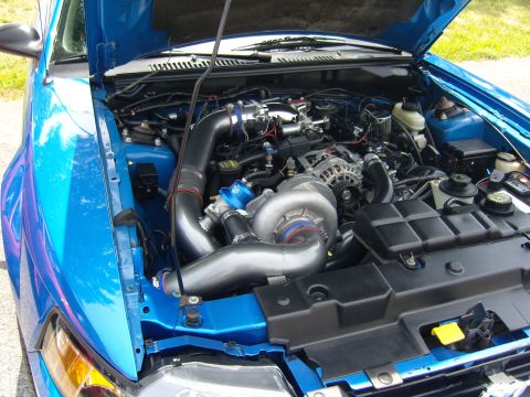 2007 Ford Mustang - The engine bay of a blue car features a prominent turbocharger and intercooler system.