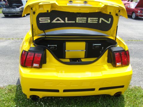 2007 Ford Mustang - A yellow Saleen Mustang is viewed from the rear with its trunk open, revealing custom audio equipment and prominent Saleen branding.
