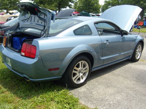 2007 Ford Mustang - Light blue 2007 Ford Mustang coupe with trunk and hood open, parked outdoors.