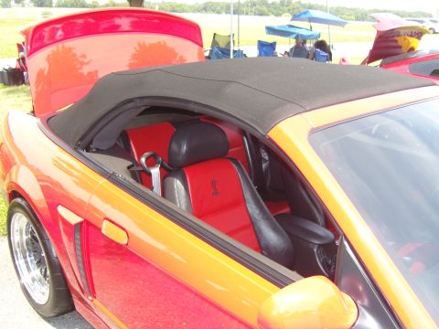 2007 Ford Mustang - Red and orange convertible with black top and custom interior. Hood and trunk are open.
