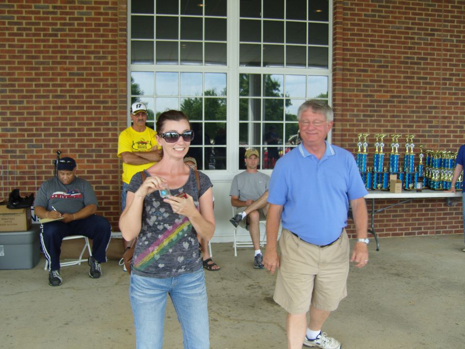 People gathered near trophies, with a brick building in the background