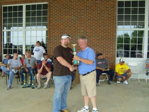 2007 Ford Mustang - Two men exchange a trophy during an outdoor award ceremony with spectators in the background.