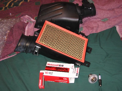 Ford airbox, air filter, Motorcraft spark plug boxes and a plug on green cloth