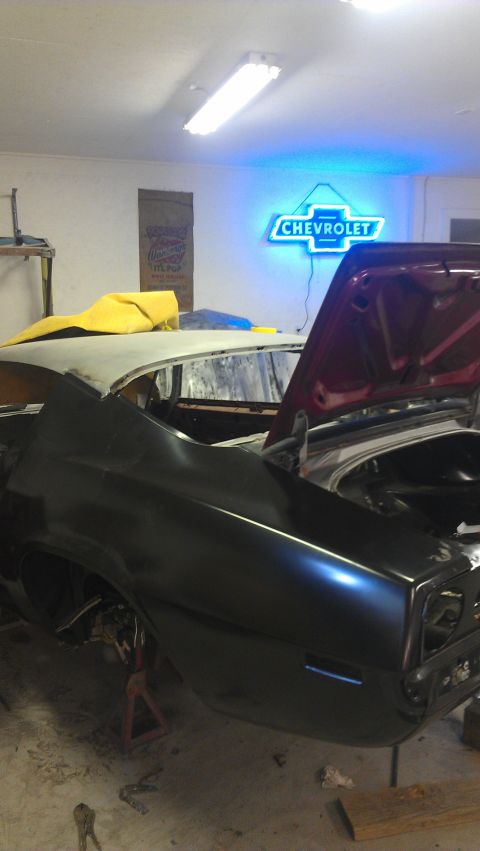 1980 Pontiac Trans Am - Car body in a garage, possibly undergoing restoration, with a prominent Chevrolet sign in the background.