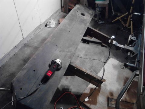 1989 Ford Bronco - A metal plate and a grinder are on a concrete floor, supported by wooden beams in a workshop.