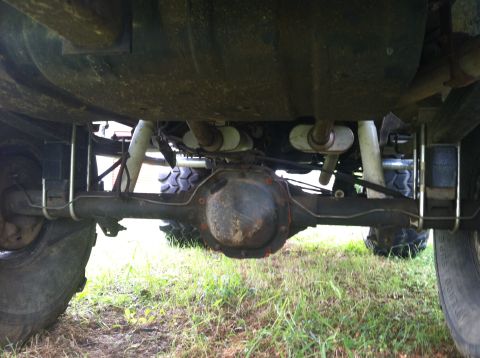 1991 Ford Bronco - The rear axle and exhaust system of an unidentified vehicle are visible from below.