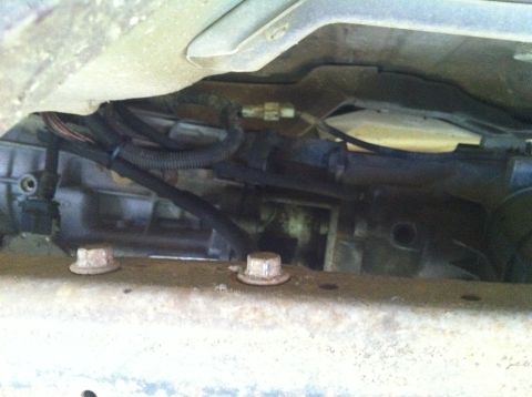 1991 Ford Bronco - Close-up view of the transmission and wiring components from underneath a vehicle.