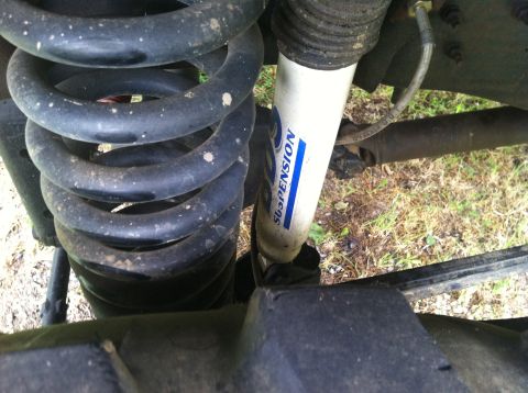 1991 Ford Bronco - The image shows a close-up view of a vehicle's suspension system, focusing on a coil spring and a shock absorber.