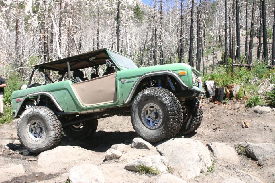 Green off-road Bronco on rocks, removable top, lifted suspension