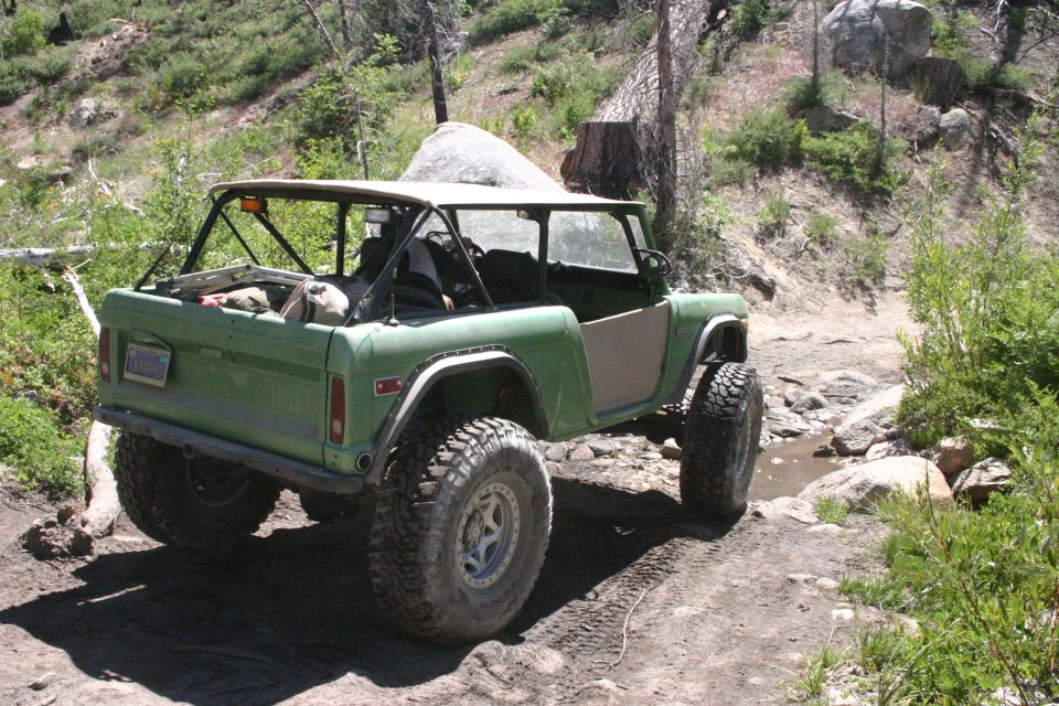 Green off-road SUV with a roll cage and large tires on a dirt path