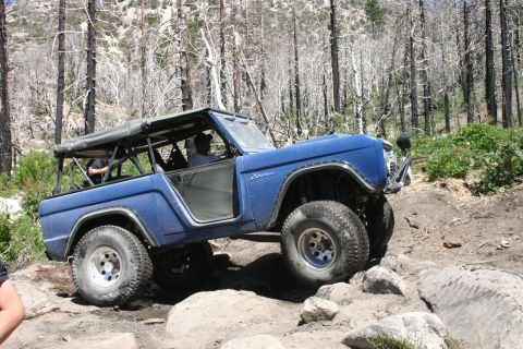 1991 Ford Bronco - This modified first-generation Ford Bronco is shown tackling a rocky trail in a wooded area.