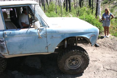 1991 Ford Bronco - A light blue Ford Bronco with a white roof sits on a dirt road, with a man inside and a woman standing nearby.
