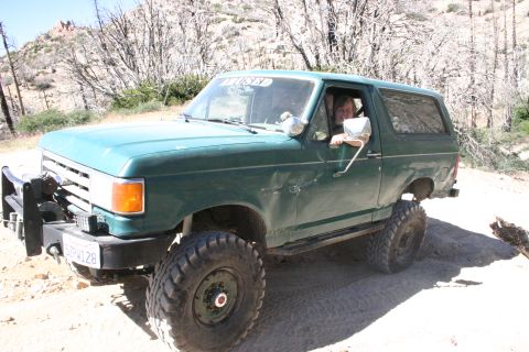 1991 Ford Bronco - This lifted 1991 Ford Bronco navigates a dusty, off-road trail with large tires and a brush guard.