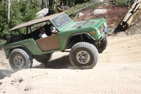 1991 Ford Bronco - This modified Ford Bronco is tackling a challenging off-road trail with large tires and a lifted suspension.
