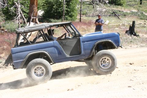 1991 Ford Bronco - This modified Bronco is kicking up dust on a trail, with a bystander watching.