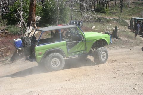 1991 Ford Bronco - Modified green Bronco navigates a dusty trail, with another vehicle visible in the background.