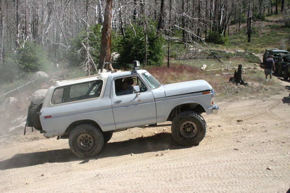 White 1978 Ford Bronco off-roading with a spare tire mounted on the back