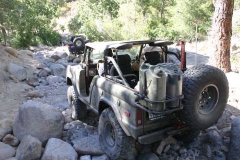 1991 Ford Bronco - This modified Ford Bronco navigates a challenging rocky terrain with multiple vehicles in the background.