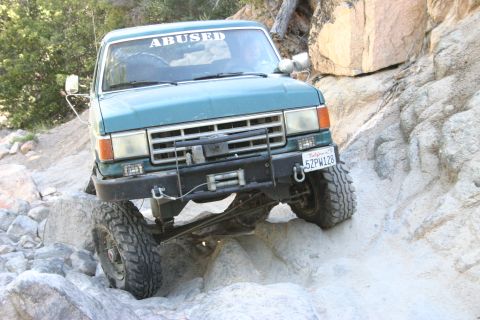 1991 Ford Bronco - This 1991 Ford Bronco navigates a rocky trail, its off-road capabilities with a winch and a prominent "ABUSED" sticker.