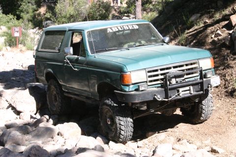 1991 Ford Bronco - This 1991 Ford Bronco navigates a rocky trail, its "ABUSED" windshield sticker hinting at its off-road adventures.