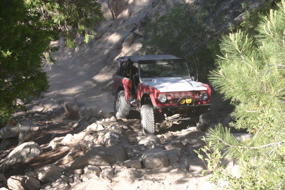 Red and white Ford Bronco on rocky trail