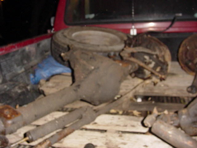 Rear axle assemblies and a spare tire in the bed of a red pickup truck