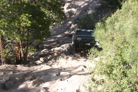 1991 Ford Bronco - This 1991 Ford Bronco tackles a challenging, rocky trail surrounded by trees and terrain.