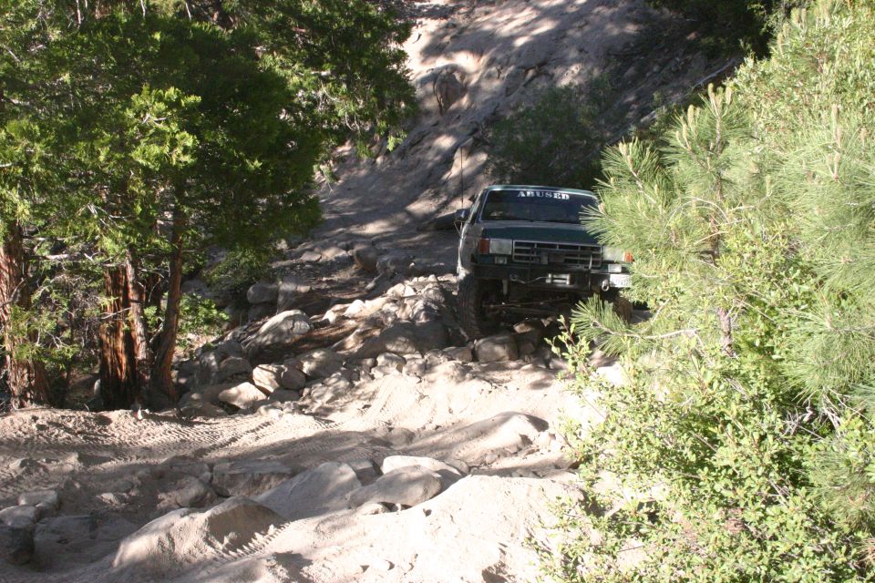 Green 1991 Ford Bronco navigating a rocky off-road trail