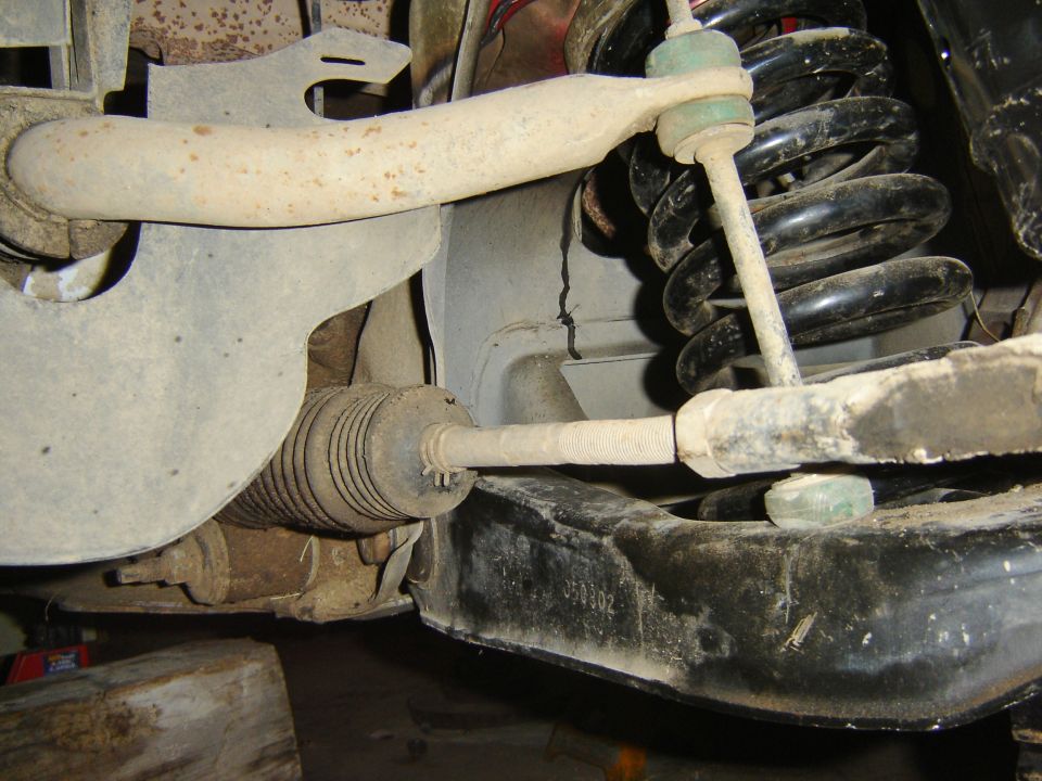 Front suspension underside: coil spring, tie rod with rack boot, sway bar link, and lower control arm