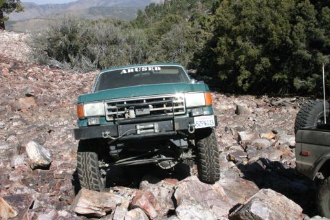 1991 Ford Bronco - This modified SUV is navigating a rocky, off-road trail with another vehicle nearby.