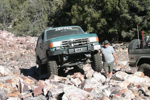 1991 Ford Bronco - This Ford Bronco, likely from the late 1980s, tackles a challenging rocky trail with another vehicle visible to the right.