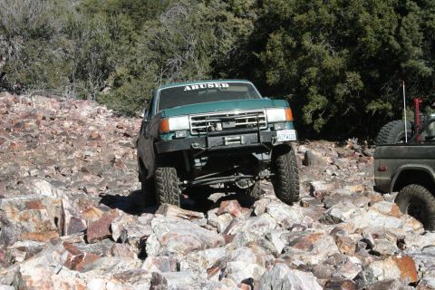 1991 Ford Bronco - Two off-road vehicles traverse a rocky, mountainous landscape.