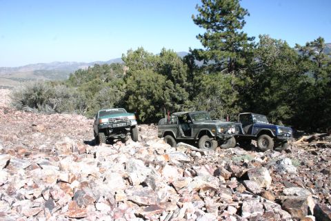 1991 Ford Bronco - Two Ford Broncos, likely from the late 1970s, navigate a , rocky landscape alongside a lighter-colored SUV.