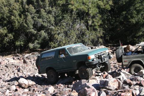 1991 Ford Bronco - A 1991 Ford Bronco is shown off-roading on a rocky trail with another vehicle nearby.