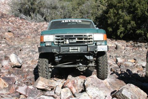 1991 Ford Bronco - This 1991 Ford Bronco is shown off-road with a winch mounted on the front bumper and a humorous "ABUSED" sticker on the windshield.