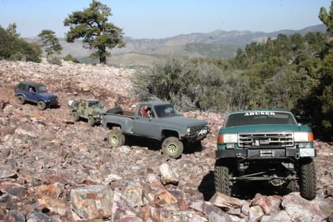 1991 Ford Bronco - Multiple off-road vehicles navigate a challenging rocky landscape under a clear sky.