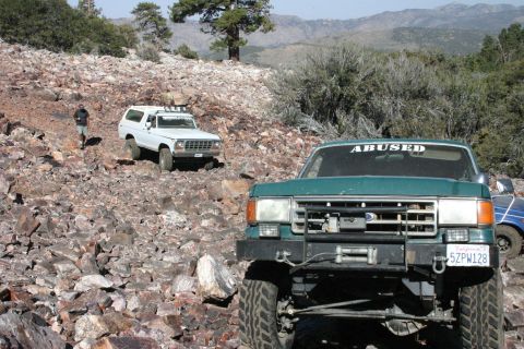 1991 Ford Bronco - Two trucks navigate a rocky, off-road trail in a mountainous, arid landscape.