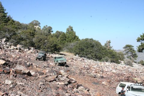 1991 Ford Bronco - Off-road vehicles traverse a challenging rocky path in a mountainous landscape.