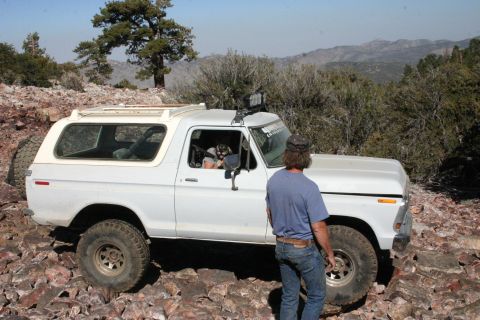 1991 Ford Bronco - This white Ford Bronco navigates a challenging rocky trail in a mountainous landscape.