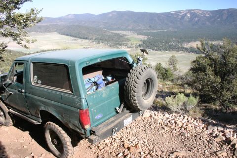 1991 Ford Bronco - This 1991 Ford Bronco is seen from the rear, parked on a rocky trail with a scenic mountain valley in the background.