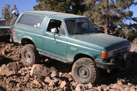1991 Ford Bronco - A 1991 Ford Bronco navigates a challenging rocky trail, with another Bronco in the background.