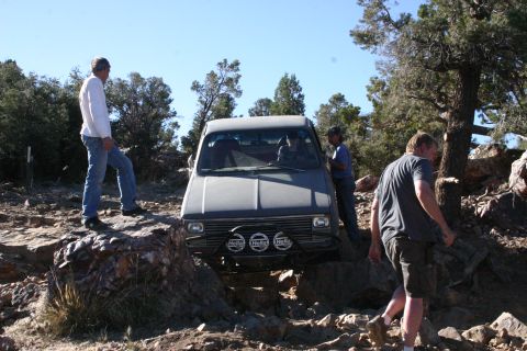 1991 Ford Bronco - A group of people watch as a pickup truck drives over rough, rocky ground.