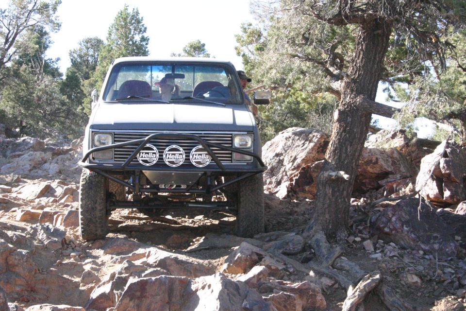 Front view of an older pickup truck modified for off-roading, with a brush guard and Hella lights