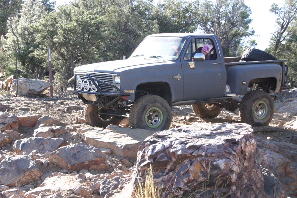 Gray pickup truck with off-road modifications driving on rocks