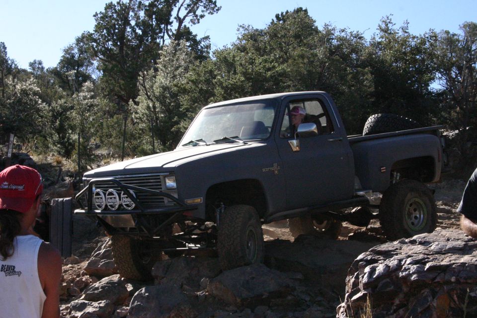 Dark gray pickup truck with off-road modifications navigating rocky terrain
