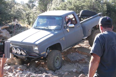1991 Ford Bronco - Modified pickup truck tackling a challenging rocky trail with a driver inside.